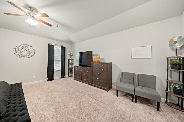 living area with baseboards, ceiling fan, visible vents, vaulted ceiling, and light colored carpet