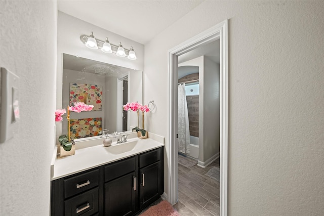 bathroom featuring wood tiled floor, a shower with shower curtain, vanity, and a textured wall