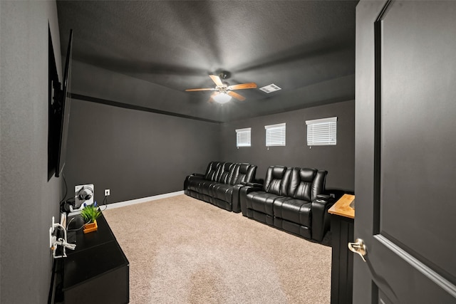 carpeted home theater with baseboards, visible vents, ceiling fan, and a textured ceiling