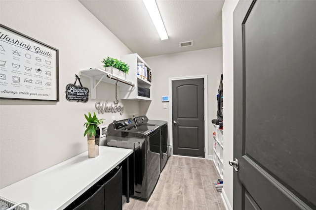 washroom with laundry area, light wood-style flooring, independent washer and dryer, and visible vents