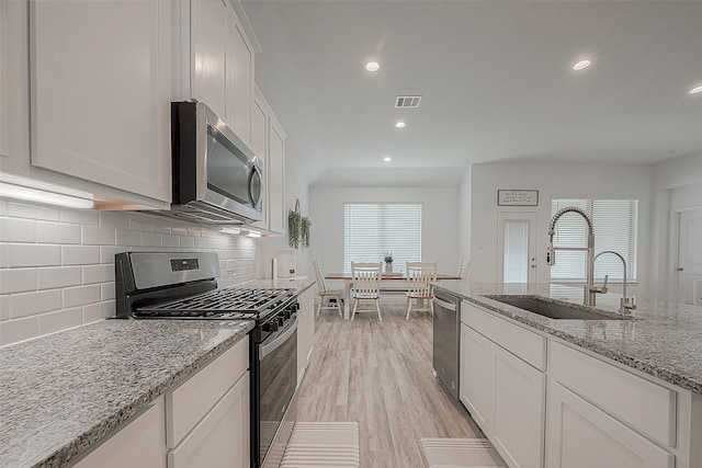 1672 Happy Valley St, Montgomery, TX 77316 - kitchen featuring a sink, stainless steel appliances, visible vents, light wood-style flooring, and white cabinets
