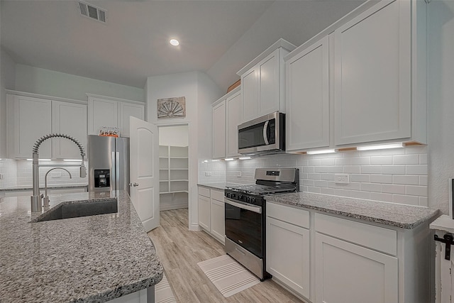 1672 Happy Valley St, Montgomery, TX 77316 - kitchen with appliances with stainless steel finishes, visible vents, decorative backsplash, and a sink