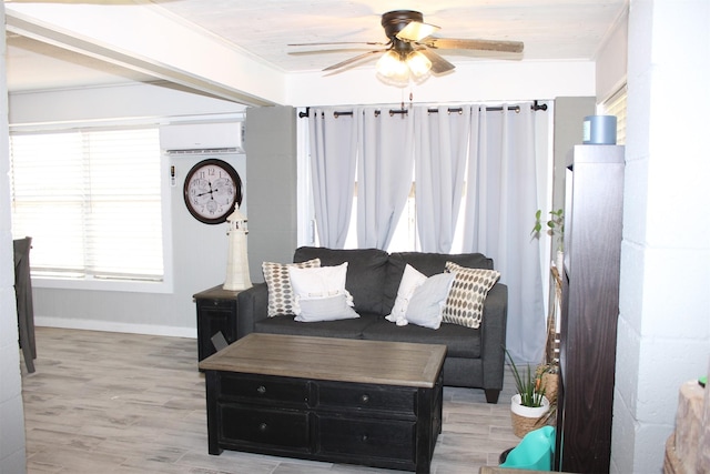 living room with a wall unit AC, light wood-type flooring, baseboards, ceiling fan, and ornamental molding