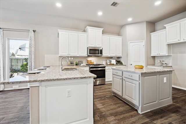kitchen featuring a sink, a peninsula, stainless steel appliances, visible vents, and white cabinetry