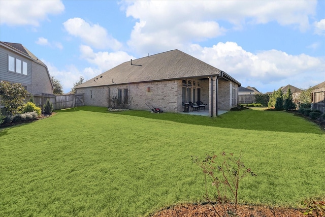 back of house with a yard, a patio, brick siding, and a fenced backyard