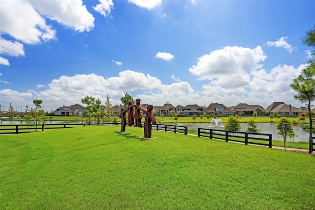view of yard featuring fence, a water view, and a residential view
