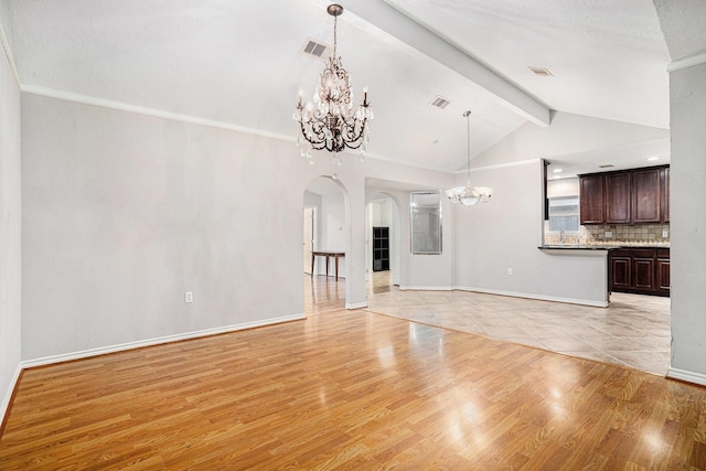 unfurnished living room featuring lofted ceiling with beams, visible vents, baseboards, arched walkways, and a chandelier