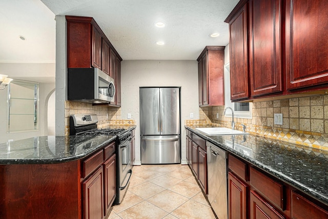 kitchen with a sink, stainless steel appliances, backsplash, and reddish brown cabinets