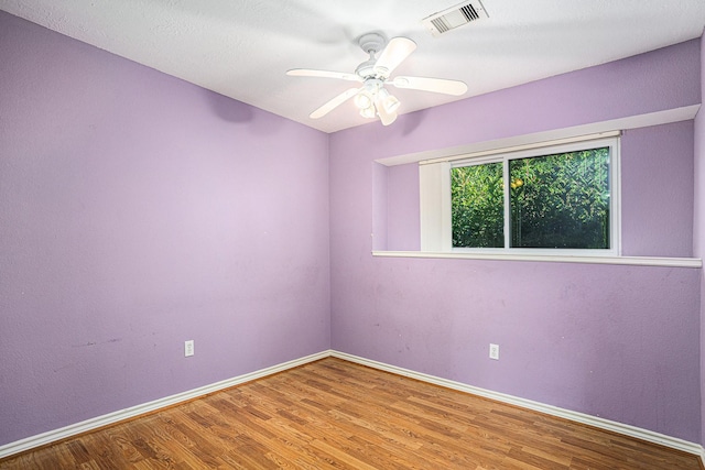 unfurnished room featuring a ceiling fan, visible vents, wood finished floors, and baseboards