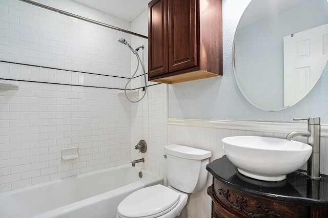 bathroom featuring bathing tub / shower combination, toilet, a wainscoted wall, and vanity