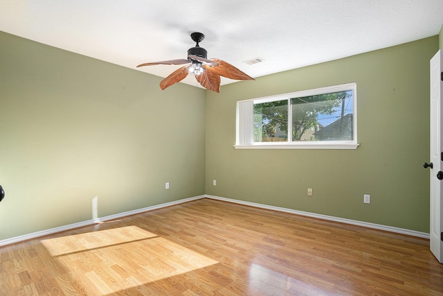 spare room with baseboards, visible vents, wood finished floors, and a ceiling fan