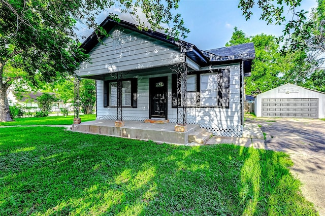 view of front of home featuring a front yard, an outbuilding, covered porch, and a detached garage