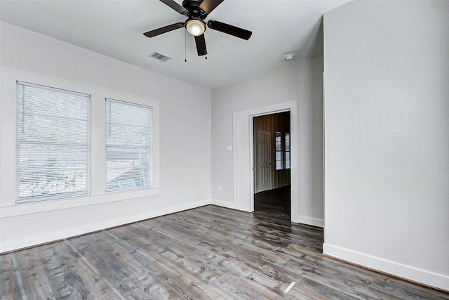 unfurnished room featuring plenty of natural light, wood finished floors, ceiling fan, and baseboards
