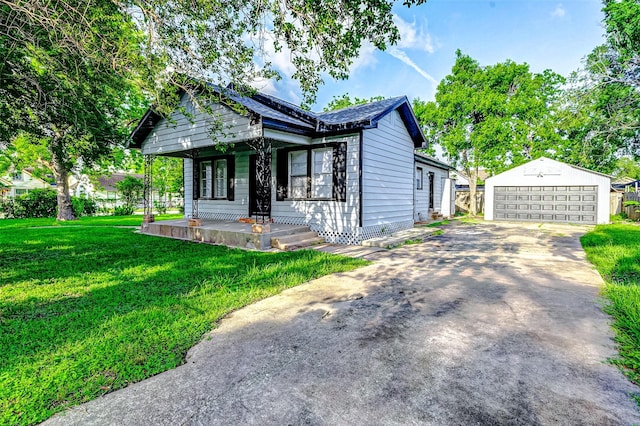 view of front facade with covered porch, an outdoor structure, a front yard, and a detached garage