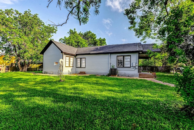 rear view of property featuring a yard and fence