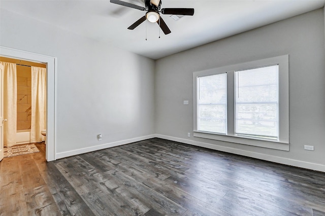 unfurnished room with a ceiling fan, baseboards, and dark wood-type flooring