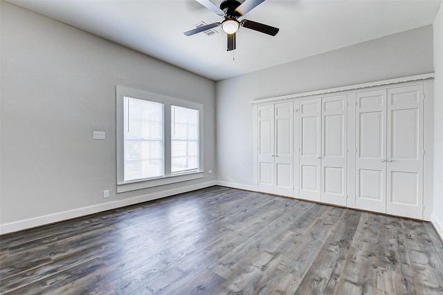 unfurnished bedroom featuring wood finished floors, baseboards, a closet, and a ceiling fan