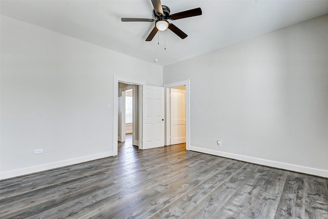 spare room featuring baseboards, wood finished floors, and a ceiling fan