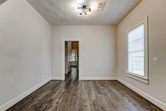 spare room featuring baseboards, dark wood-style flooring, and visible vents