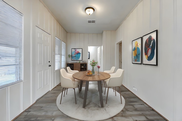 dining room featuring healthy amount of natural light, wood finished floors, and a decorative wall