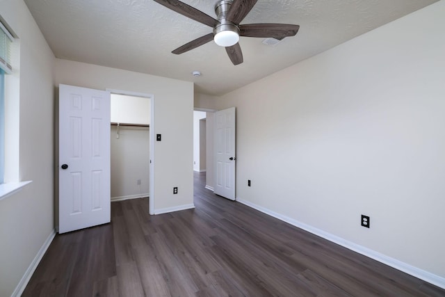 6902 Woodland Oaks, Magnolia, TX 77354 - unfurnished bedroom with a closet, dark wood finished floors, a ceiling fan, a walk in closet, and baseboards