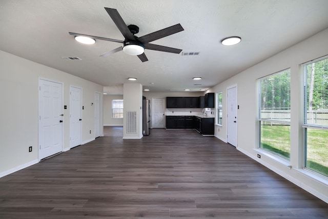 6902 Woodland Oaks, Magnolia, TX 77354 - unfurnished living room featuring dark wood finished floors, visible vents, baseboards, and ceiling fan