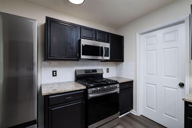 6902 Woodland Oaks, Magnolia, TX 77354 - kitchen featuring backsplash, dark wood-style flooring, appliances with stainless steel finishes, and dark cabinetry