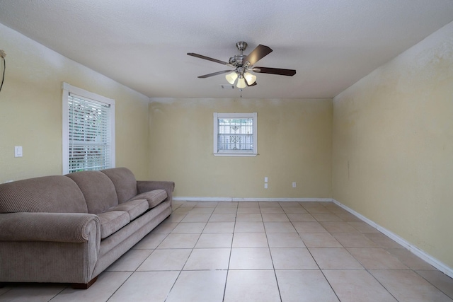 living room featuring baseboards, light tile patterned floors, and ceiling fan