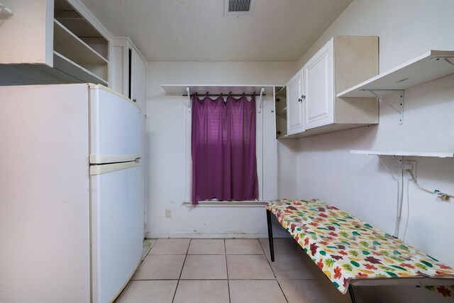 kitchen featuring light tile patterned floors, freestanding refrigerator, open shelves, white cabinetry, and visible vents