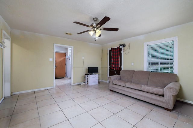 living area with a ceiling fan, a textured ceiling, visible vents, baseboards, and light tile patterned flooring