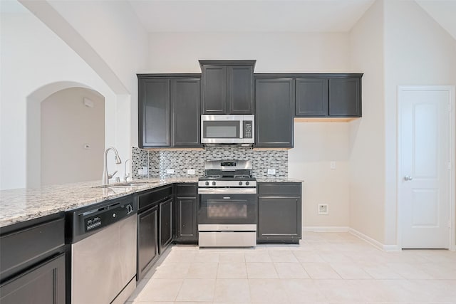 19911 Whistle Creek Ln, Cypress, TX 77433 - kitchen featuring a sink, stainless steel appliances, tasteful backsplash, arched walkways, and light stone countertops