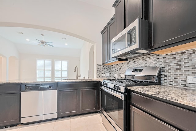 19911 Whistle Creek Ln, Cypress, TX 77433 - kitchen with a sink, light stone counters, ceiling fan, arched walkways, and appliances with stainless steel finishes