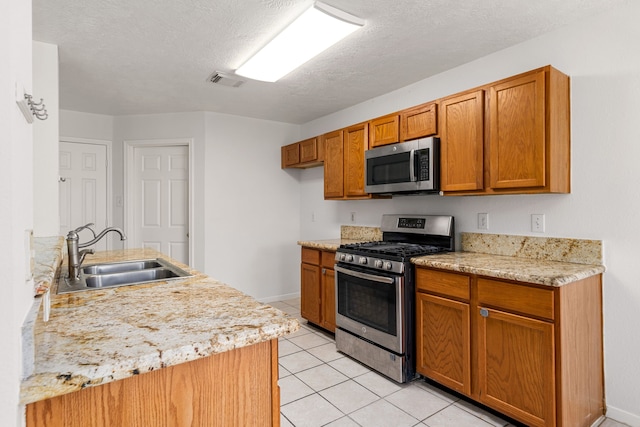 5315 Cilantro Ln, Baytown, TX 77521 - kitchen with stainless steel appliances, a sink, light tile patterned floors, brown cabinetry, and baseboards