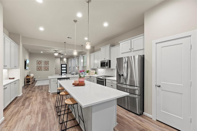 7015 Winterberry Glen Ln, Katy, TX 77493 - kitchen with a ceiling fan, a peninsula, backsplash, light countertops, and appliances with stainless steel finishes