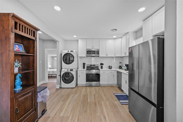1802 Ursuline St, Galveston, TX 77550 - kitchen with stacked washing maching and dryer, stainless steel appliances, white cabinets, backsplash, and light countertops