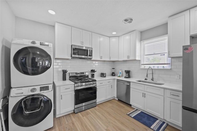 1802 Ursuline St, Galveston, TX 77550 - kitchen with a sink, stacked washing maching and dryer, light wood-type flooring, light countertops, and appliances with stainless steel finishes