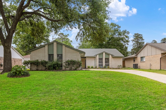 mid-century inspired home featuring brick siding, a front yard, driveway, and central air condition unit