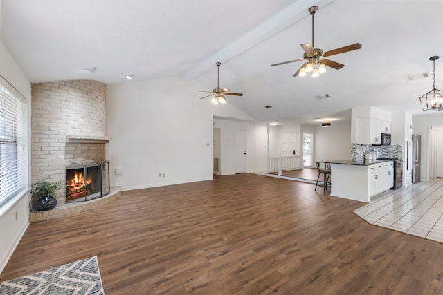 unfurnished living room with wood finished floors, a fireplace, ceiling fan, and baseboards