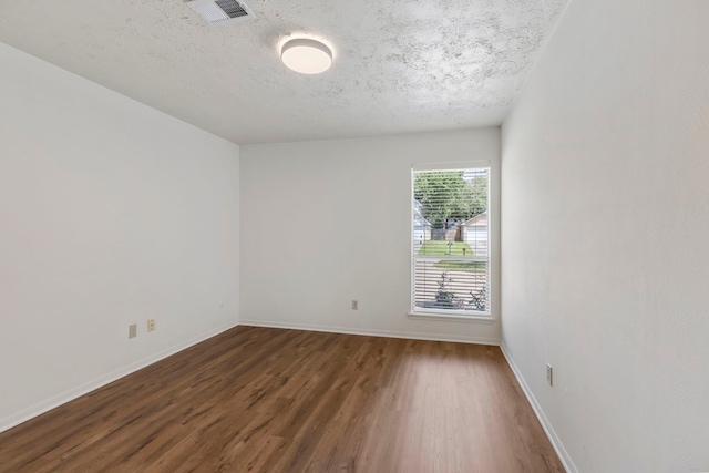 empty room with wood finished floors, baseboards, and a textured ceiling