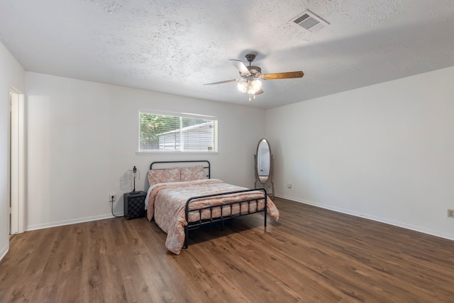 bedroom with wood finished floors, a textured ceiling, baseboards, and ceiling fan