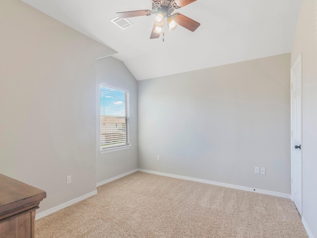 empty room featuring baseboards, ceiling fan, visible vents, vaulted ceiling, and light colored carpet