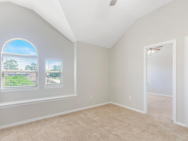 spare room with ceiling fan, lofted ceiling, and light colored carpet