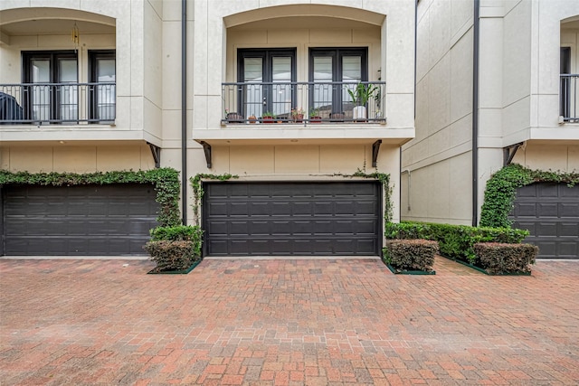 2303 Hadley St, Houston, TX 77003 - view of front of home with an attached garage, a balcony, stucco siding, and driveway