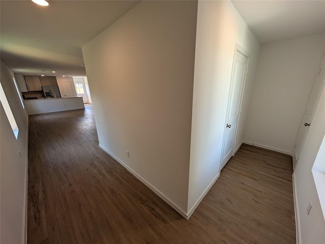 hall with dark wood-type flooring, baseboards, and recessed lighting