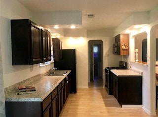 kitchen with light countertops, stainless steel range, a sink, and light wood-style floors