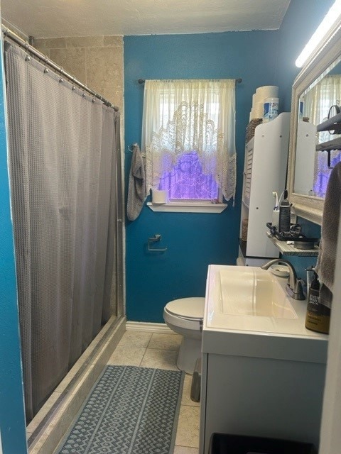full bathroom with a stall shower, tile patterned flooring, vanity, and toilet