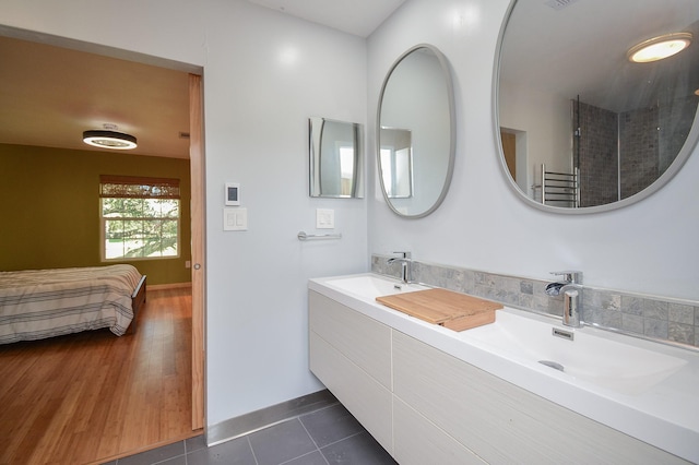 full bath with a sink, tile patterned floors, double vanity, connected bathroom, and baseboards