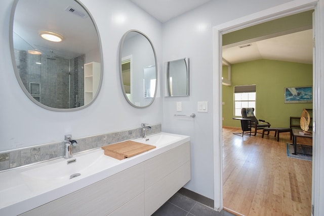 full bathroom with lofted ceiling, a shower with shower door, visible vents, a sink, and double vanity