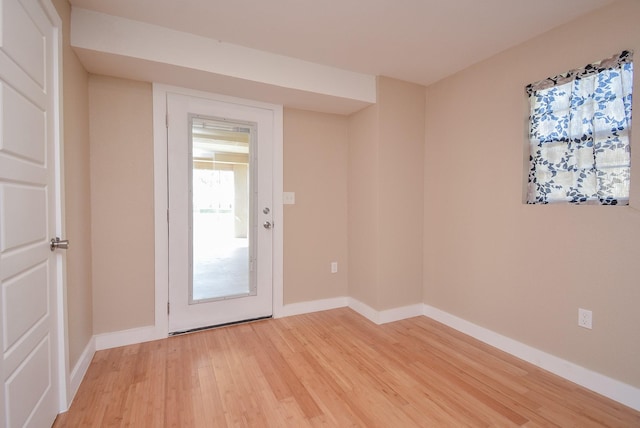 doorway to outside featuring baseboards and light wood-style floors