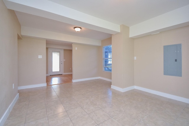 unfurnished room with baseboards, light tile patterned flooring, and electric panel